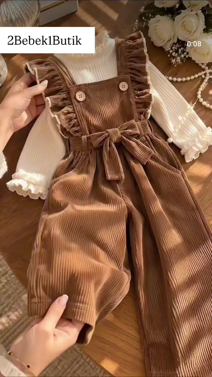Kahverengi fiyonklu, fırfır askılı salopet ve krem üst takım